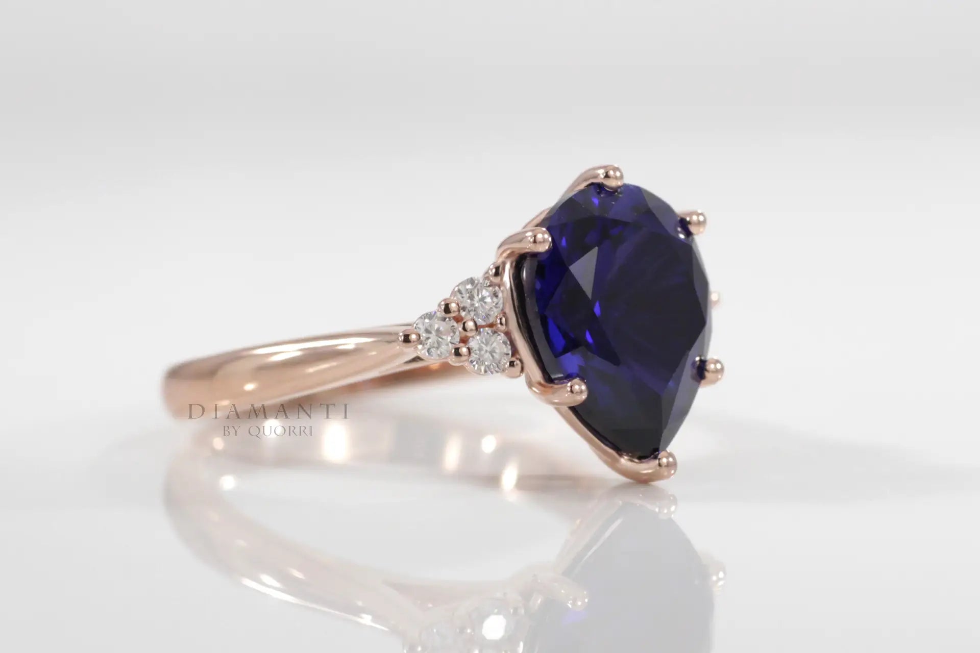 rose gold 6 prong 3 carat pear cut lab grown blue sapphire engagement ring with round diamond accents  Quorri Canada