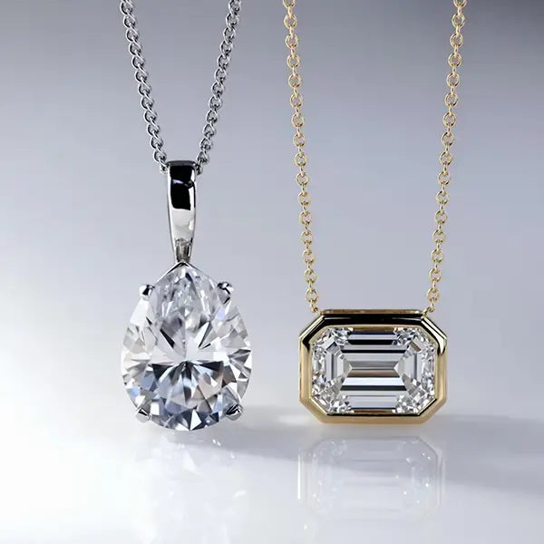 lab diamond pear pendant in white gold next to yellow gold east west emerald pendant