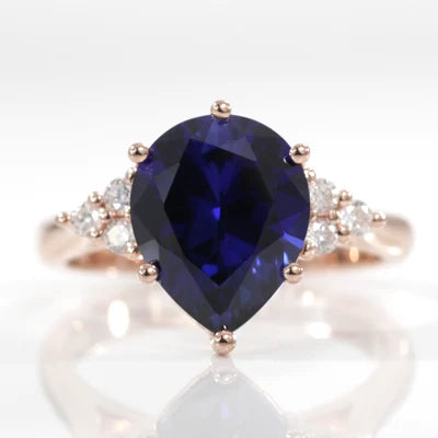 Celeste 18k yellow gold 3 carat pear lab grown blue sapphire engagement ring with white accent diamonds at Quorri