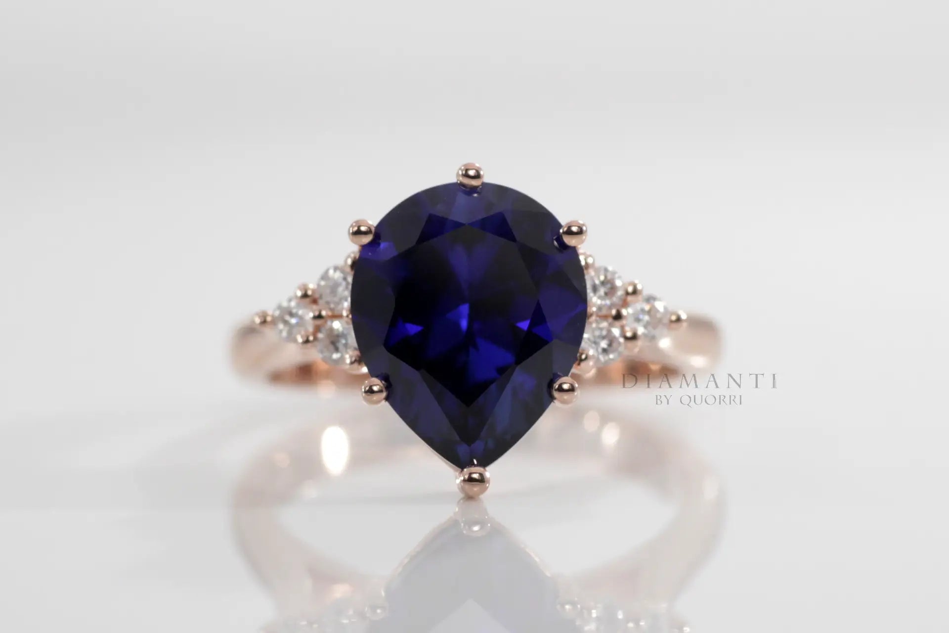 rose gold 6 prong pear cut lab grown blue sapphire engagement ring with round accents  Quorri Canada