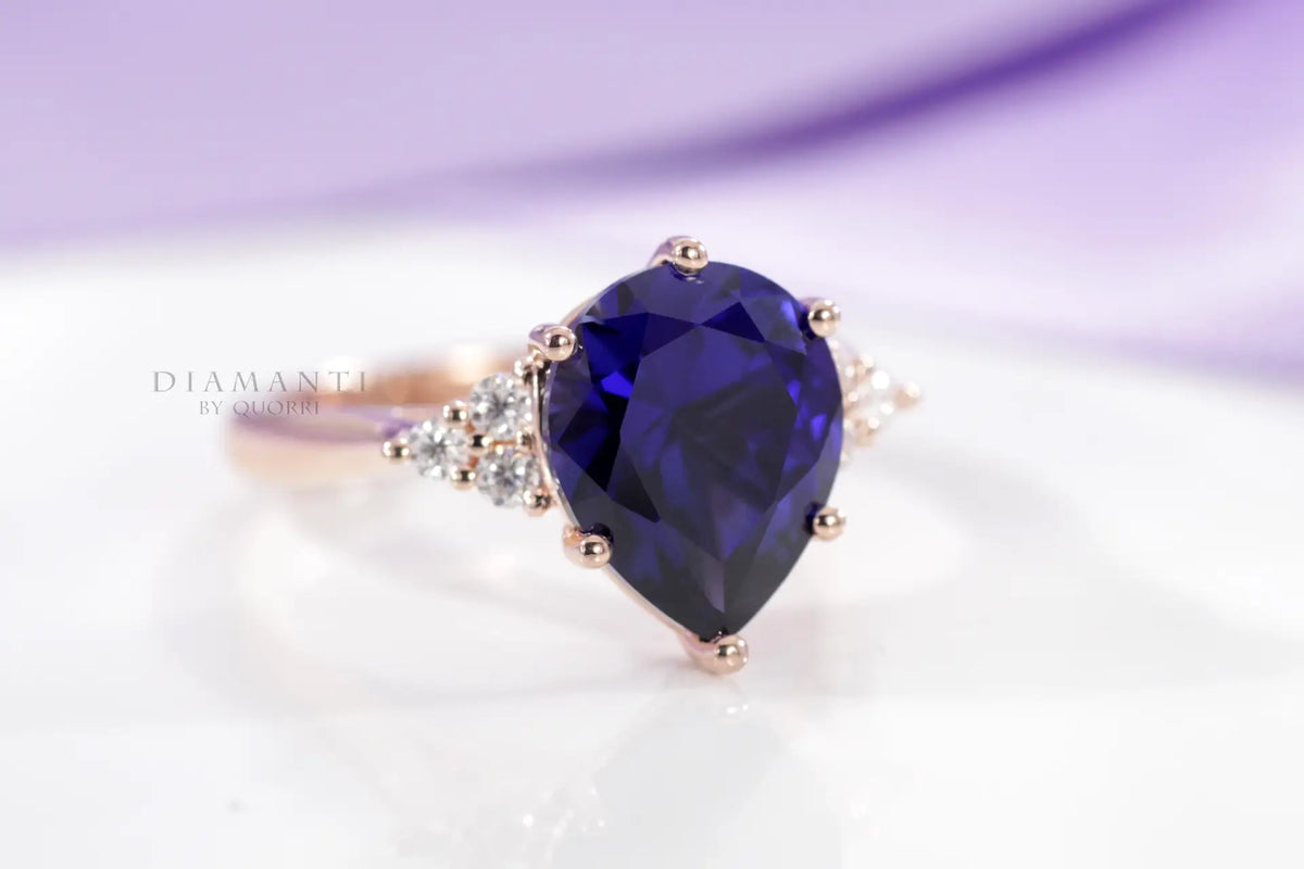 custom 6-prong rose gold 3.5 carat pear cut lab grown blue sapphire engagement ring with round diamond accents Quorri Canada