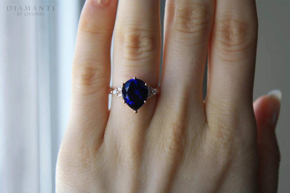 rose gold 3.5 carat pear cut lab grown blue sapphire engagement ring with round diamond accents  Quorri Canada