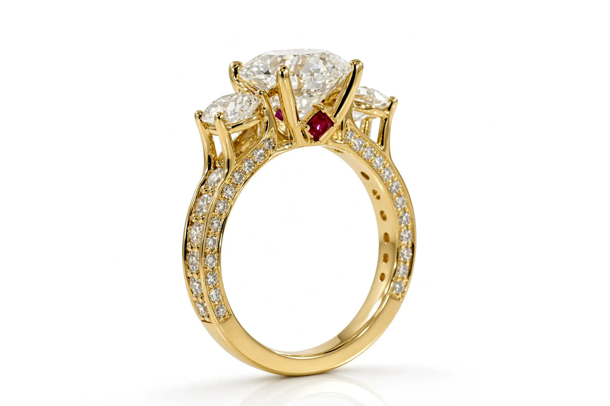 Yellow gold three-stone engagement ring with round brilliant diamond, pavé shoulders, and princess-cut ruby accent