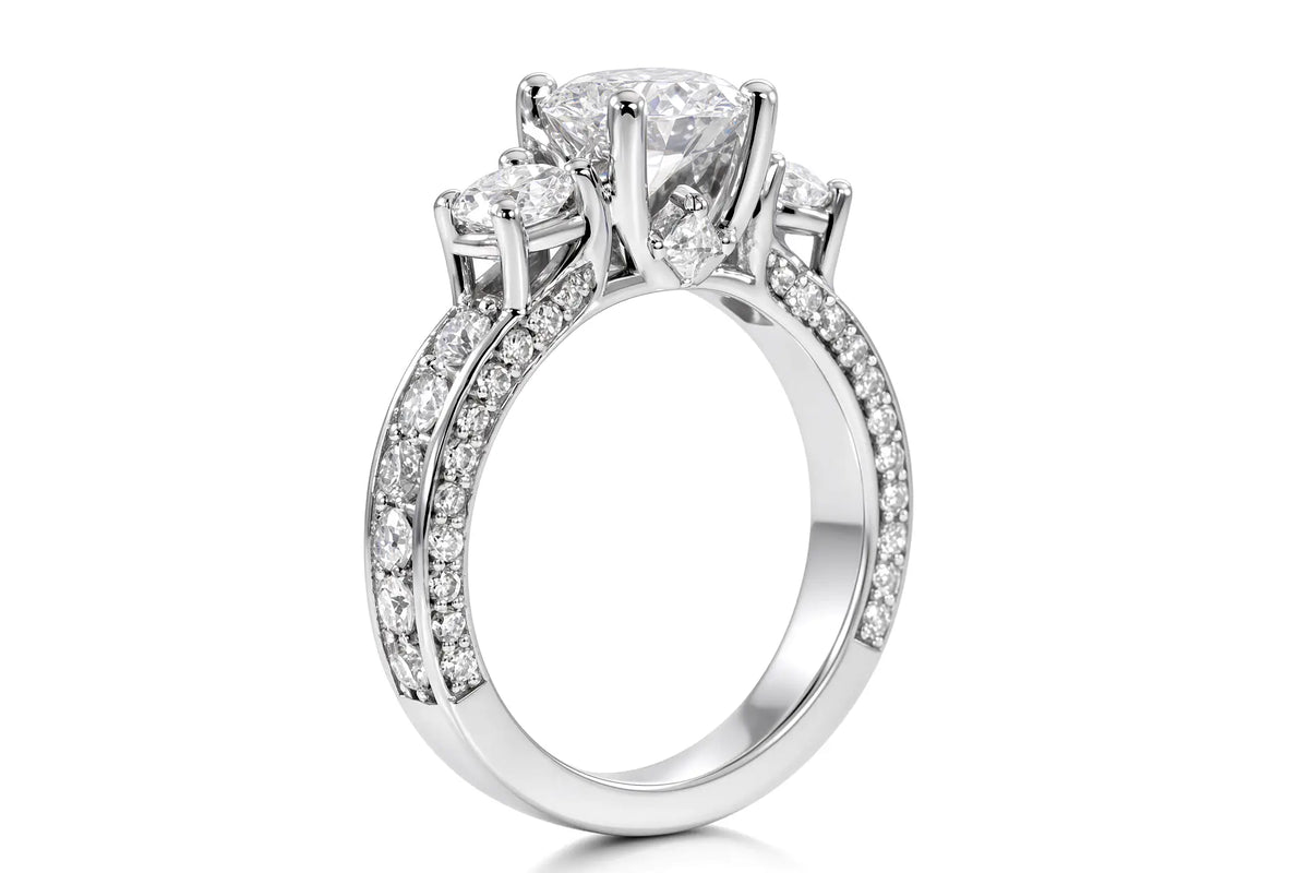 White gold three-stone engagement ring with round brilliant diamond, pavé shoulders, and princess-cut diamond accent