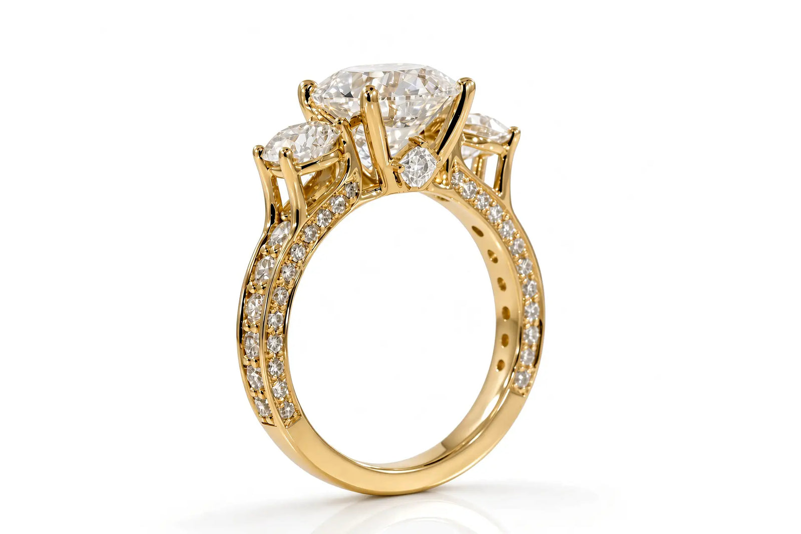 Yellow gold three-stone anniversary ring with round brilliant diamond, pavé shoulders, and princess-cut diamond accent