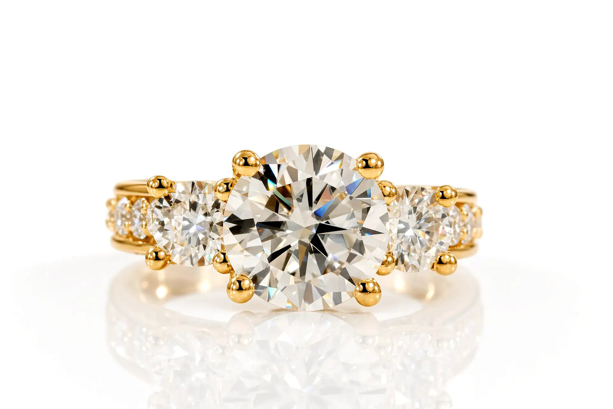 Yellow gold three-stone engagement ring with round brilliant diamond, pavé shoulders, and princess-cut ruby accent