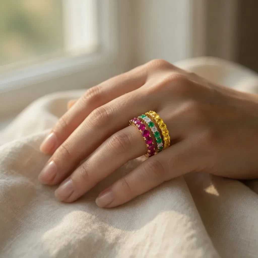 stacked on hand a ruby eternity band, diamond and emerald eternity band, yellow sapphire eternity band at Quorri
