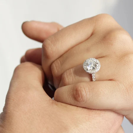 Close-up of a hand wearing a round halo white gold Aterna Gen 4 moissanite engagement ring 