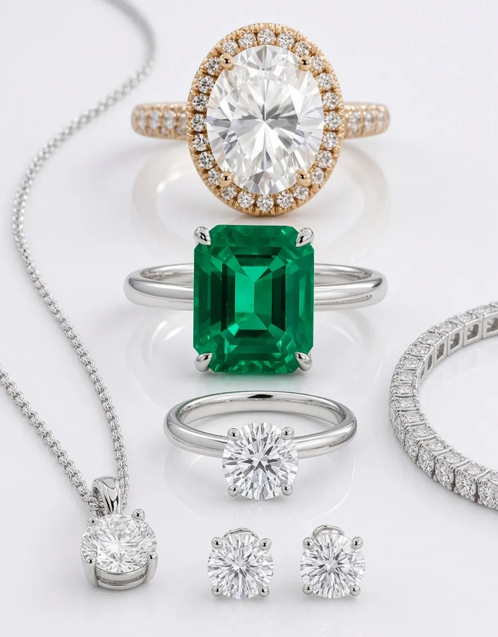 Quorri jewelry set featuring an oval diamond halo, a silver ring with a green emerald-cut center stone, a silver diamond ring, a silver necklace with a round diamond pendant, a diamond bracelet, and two diamond stud earrings.